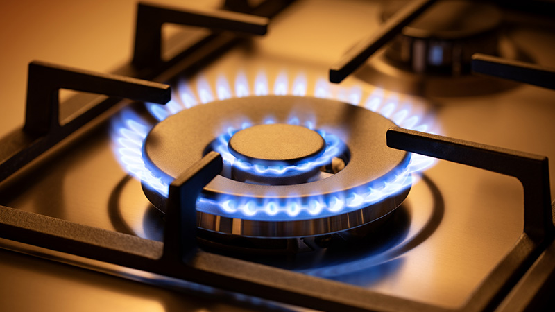 Range burner of a natural gas home stove surrounded by a blue flame.